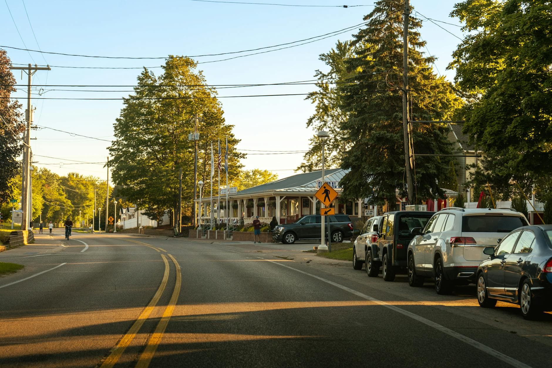 Cozy street view in Holland, Michigan showcasing parked cars, trees, and clear evening light.