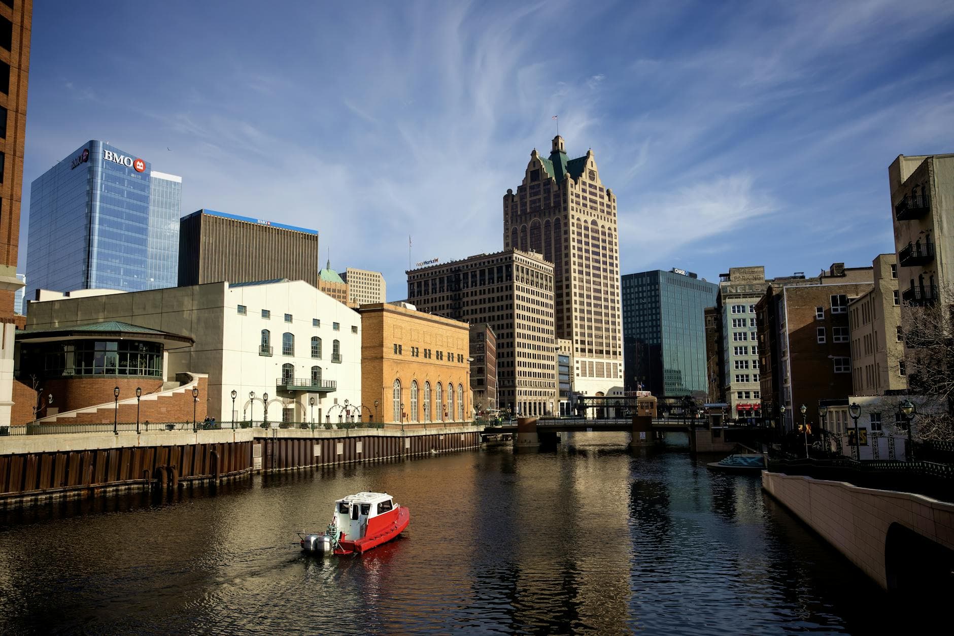 Panoramic view of Milwaukee River with iconic city buildings and a boat.