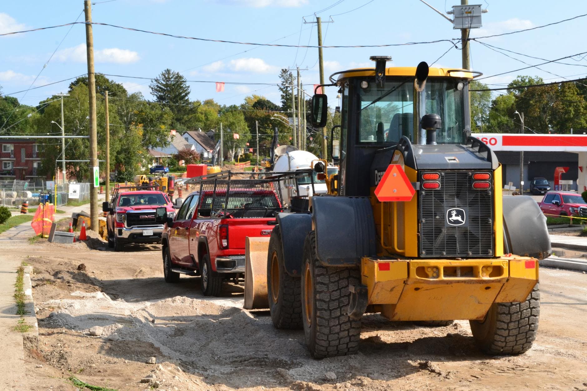 Bulldozer and trucks on a busy urban construction site with roadworks and machinery.