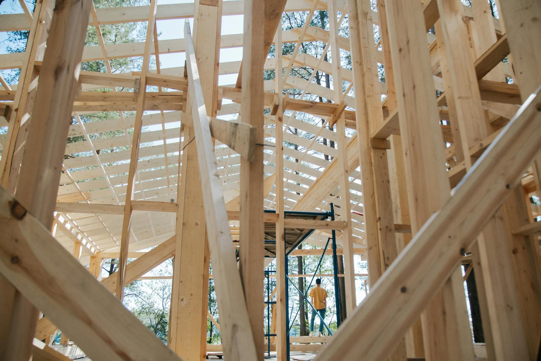 Interior view of wooden house frame under construction with visible scaffolding.