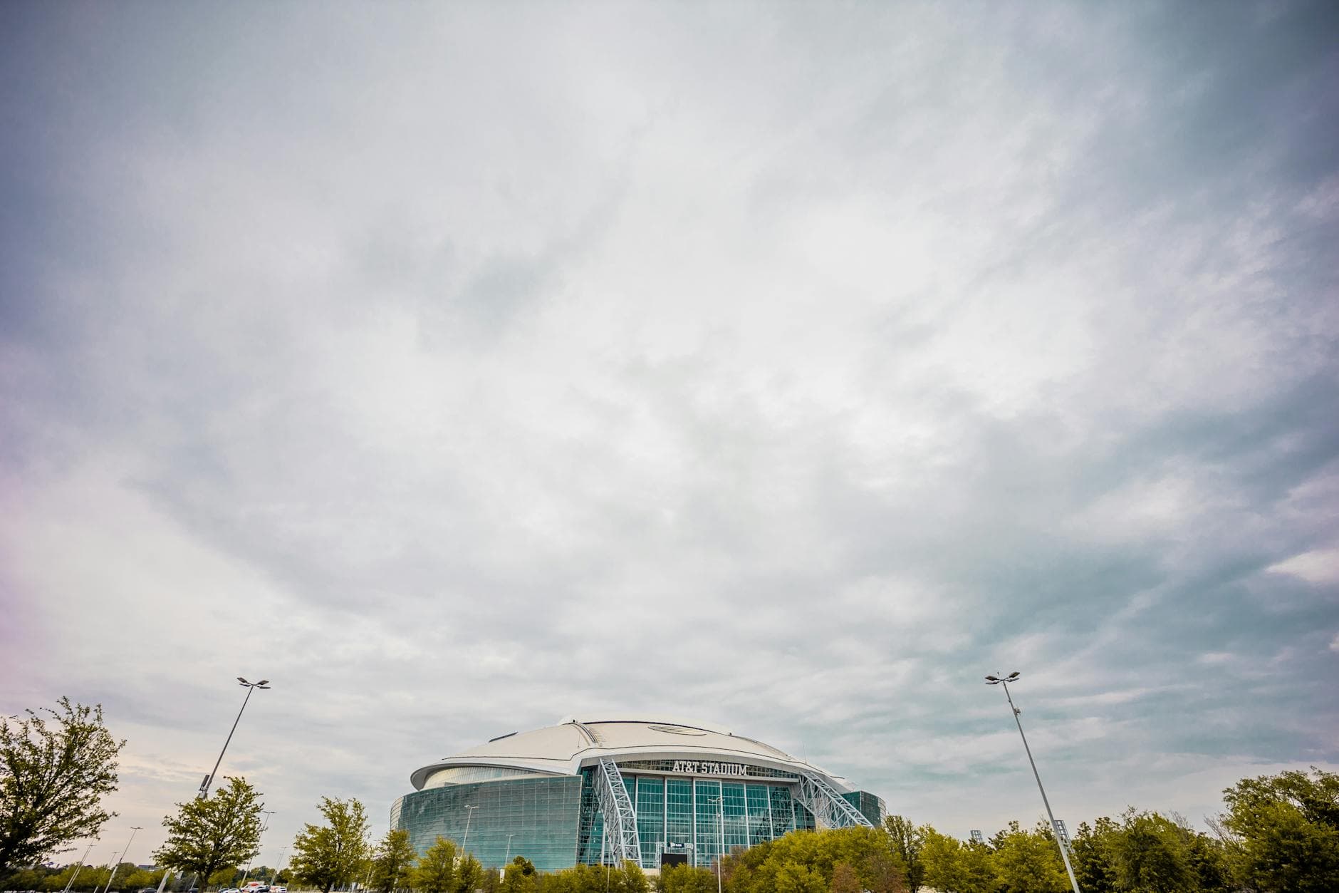 Wide-angle view of AT&T Stadium under dramatic clouds highlighting modern architectural design.