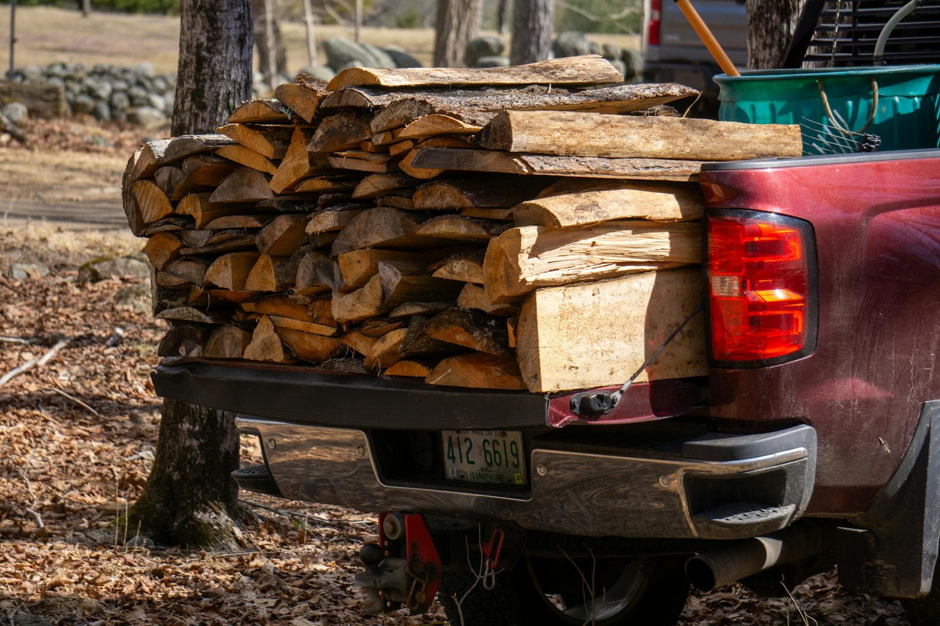A pickup truck carrying a full load of split firewood in the forest, ready for transport.