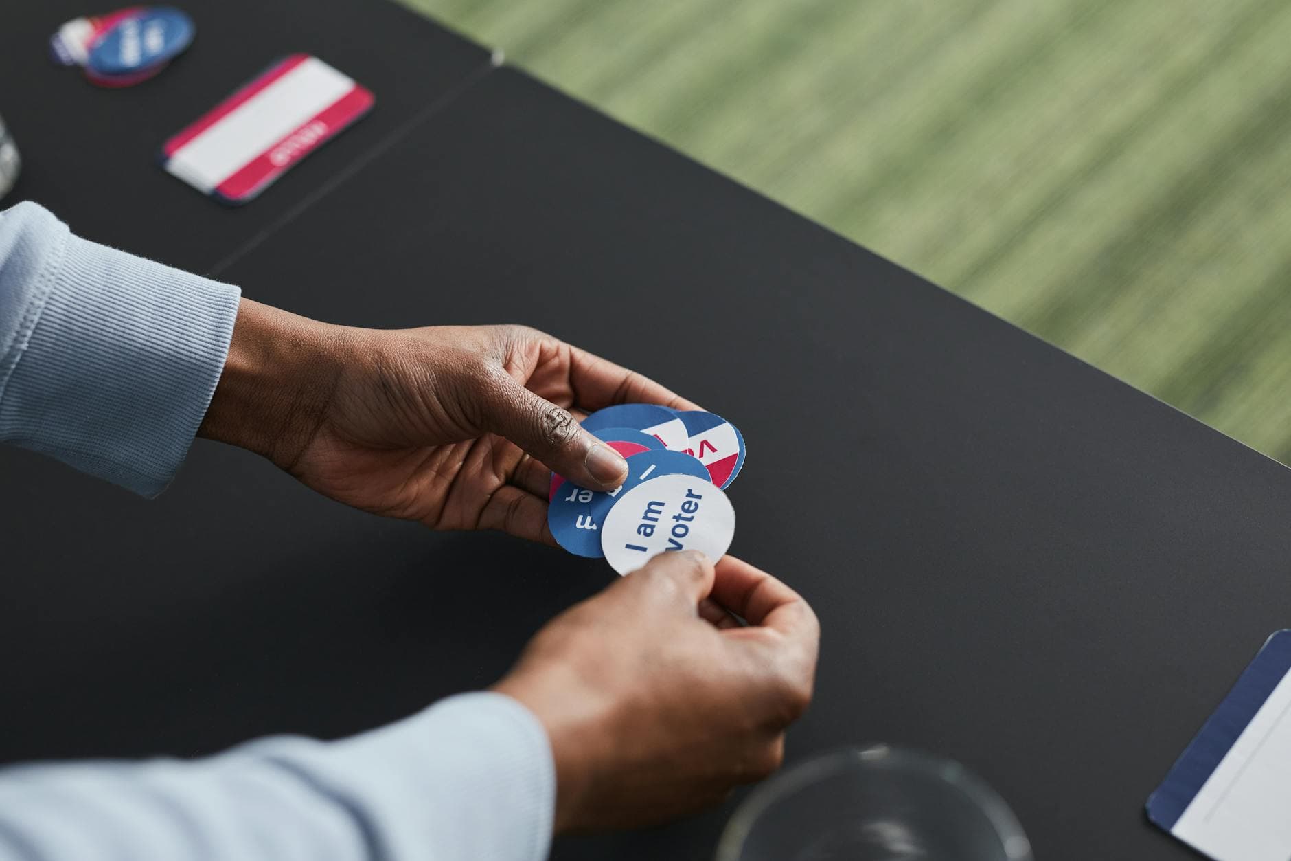 A close-up of hands holding voter stickers, symbolizing civic engagement.