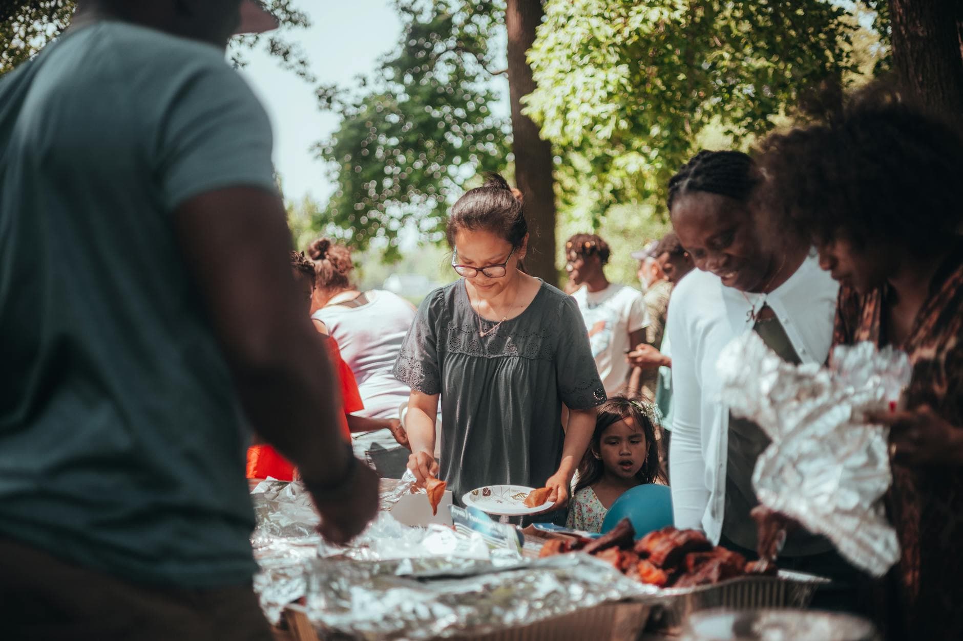 A lively barbecue gathering with diverse group outdoors enjoying food and summer weather.
