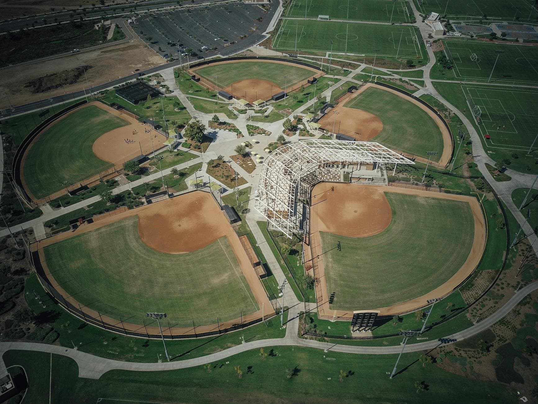 Aerial shot of a sports complex featuring multiple baseball fields in a green landscape.