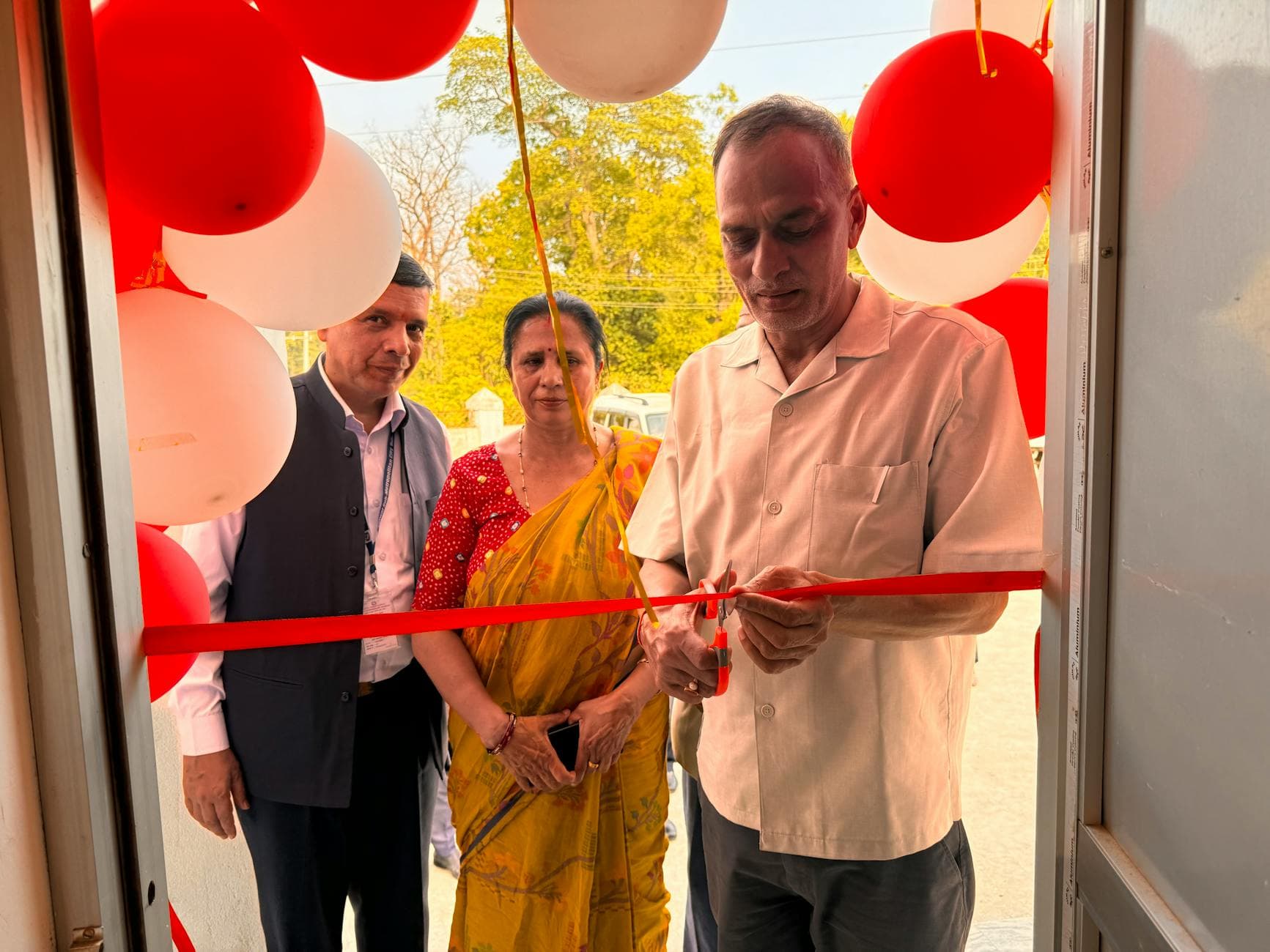 A ribbon-cutting ceremony with three adults marking an official opening.