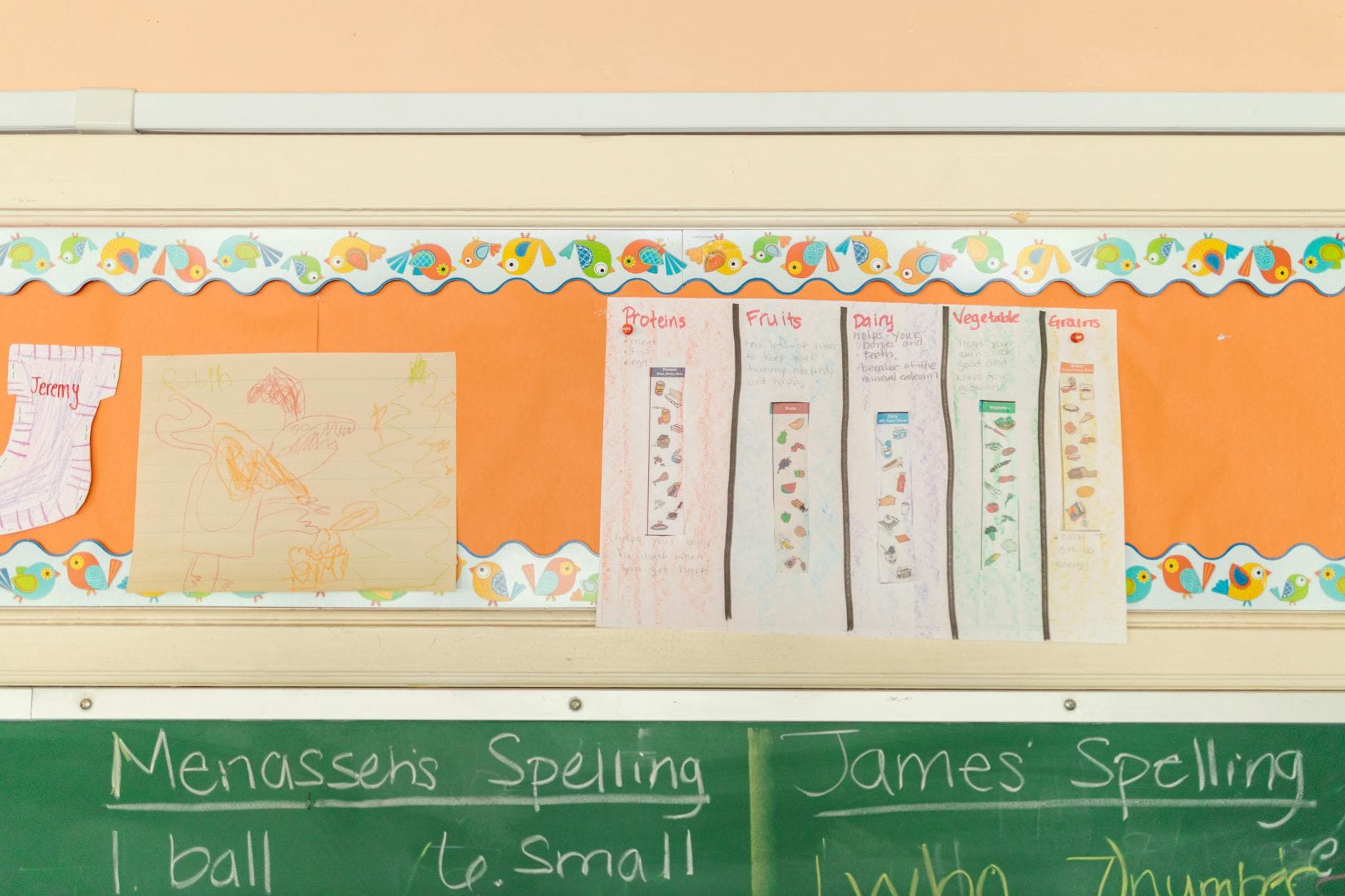 Classroom display featuring a blackboard, educational posters, and children's artwork.