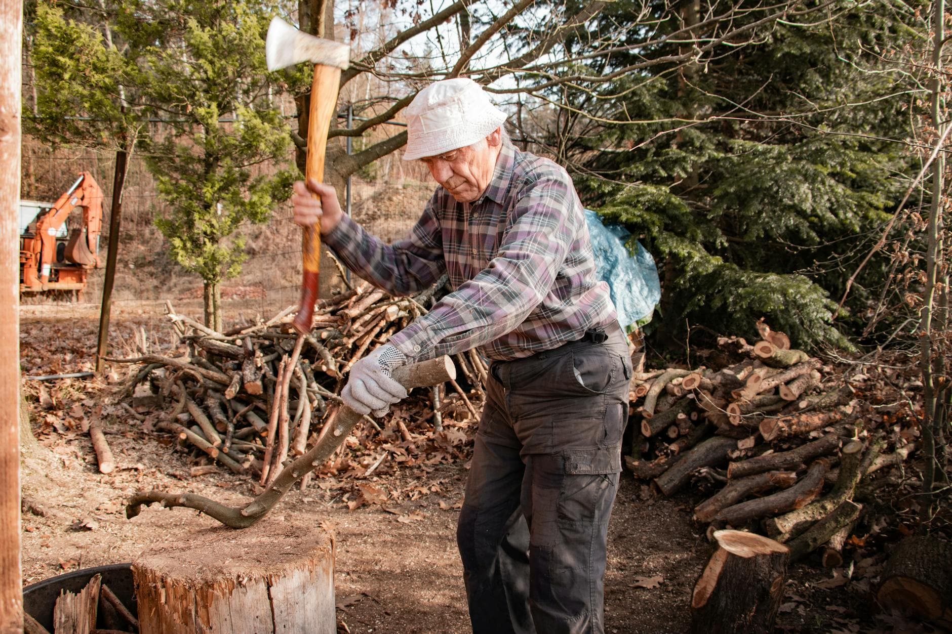 Elderly man chops wood outdoors in Bavaria, showcasing traditional craftsmanship and rural lifestyle.