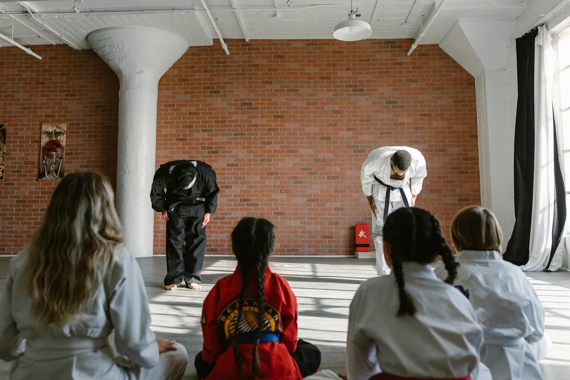 Martial arts teachers bowing to students in a dojo, demonstrating respect and discipline.