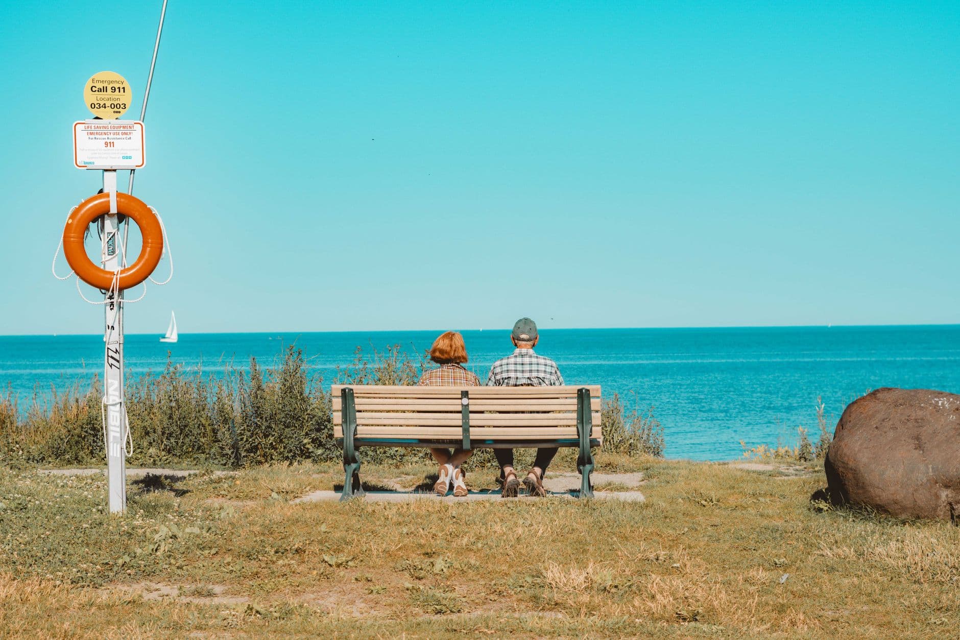 Senior couple sitting on a bench enjoying a sunny day by Lake Ontario in Toronto.