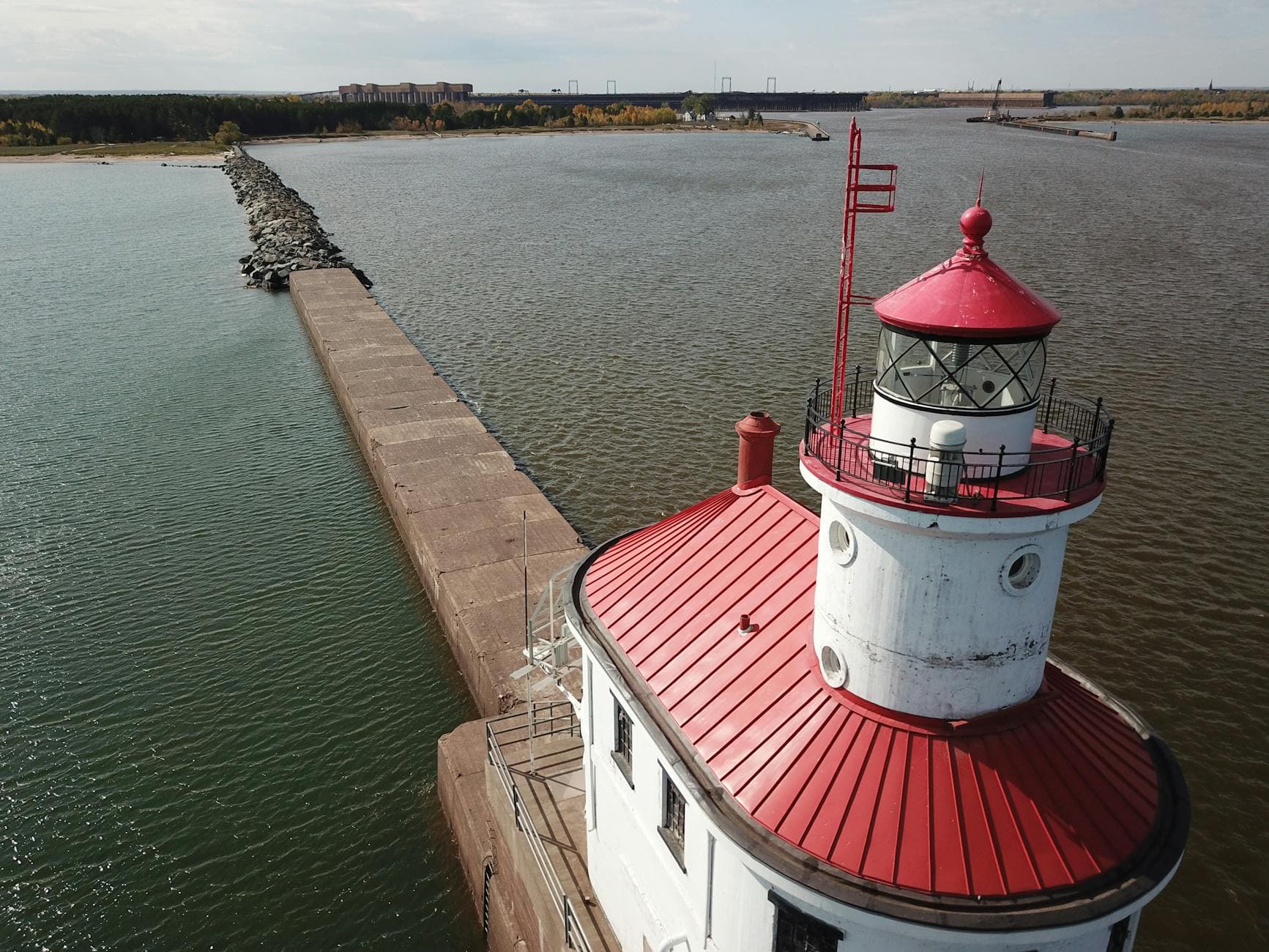 Drone shot of Wisconsin Point Lighthouse in Superior, WI, USA, surrounded by water and a pier.