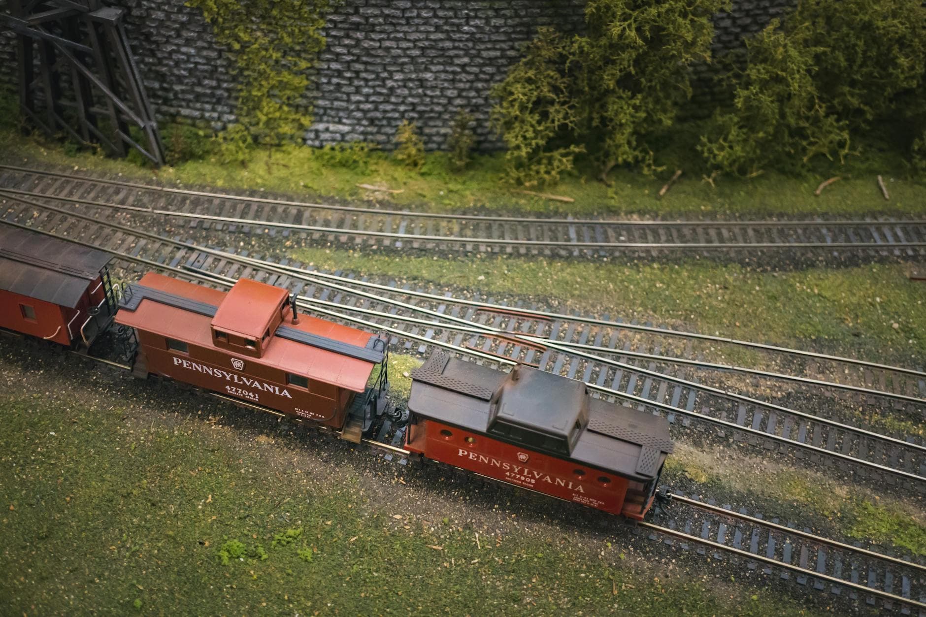 A detailed model train diorama featuring a vintage Pennsylvania locomotive on winding tracks.