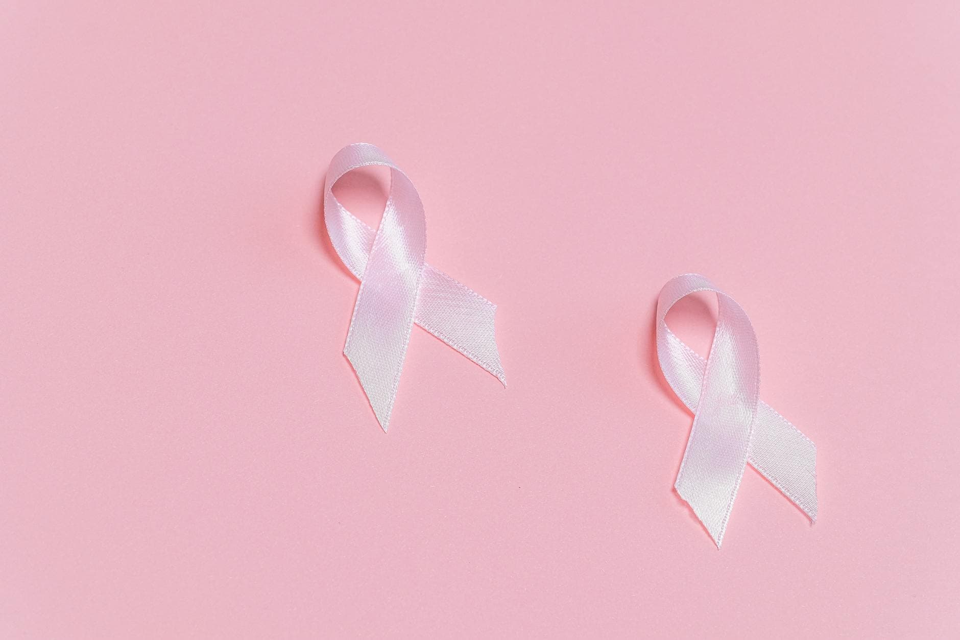 Pink ribbons symbolizing breast cancer awareness on a pink background.