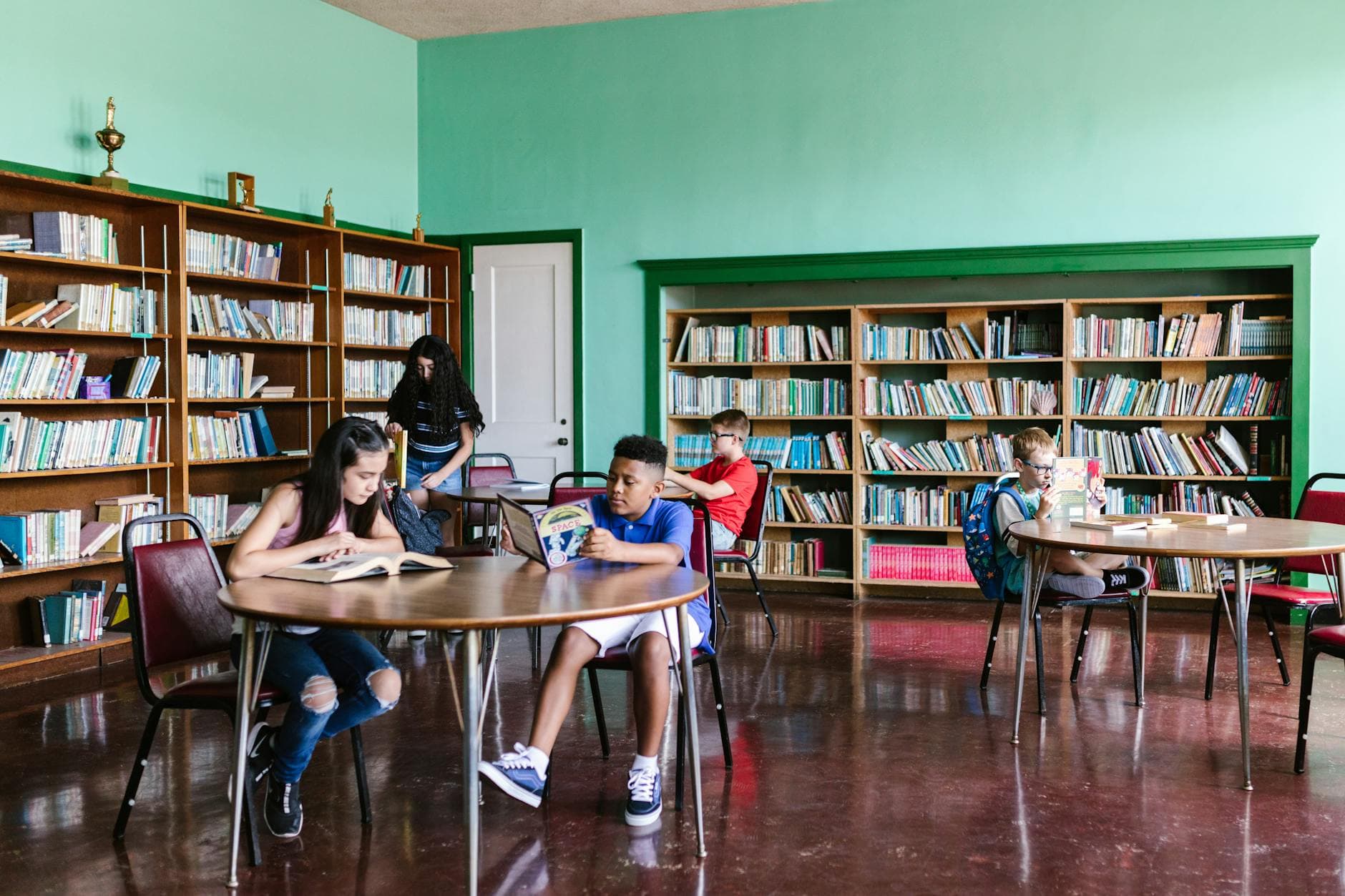 A diverse group of kids reading books in a library setting, fostering learning and togetherness.